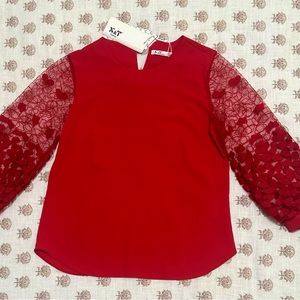 Red blouse with openwork sleeves.